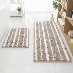 two bathroom rugs sitting on the floor in front of a bathtub and shelves