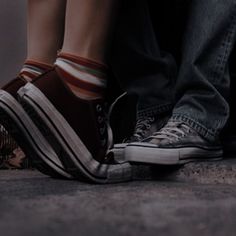 two people standing next to each other with their feet on the ground and one person wearing striped socks