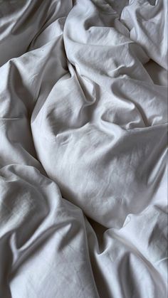 an unmade bed with white sheets and pillows