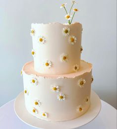 a three tiered cake with daisies on top