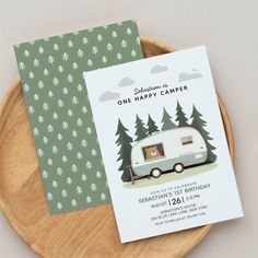 a camper birthday party card on a wooden plate with pine trees in the background