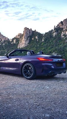 a purple convertible car parked in front of a mountain