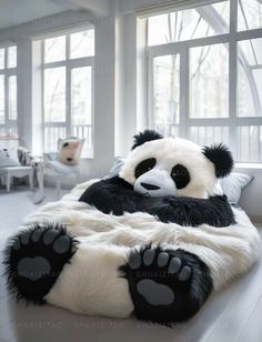 a giant panda bear sitting on top of a bed in a room with large windows