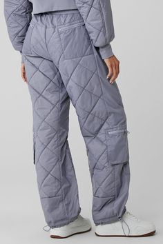 Lightly filled with a quilted finish, the Snowriders are a sleeker take on the puffer pants trend. They have a wide ribbed waistband, plenty of pockets (6 with zippers, 2 side-slit style), and bungee hems that transform the fit from wide-leg to jogger-style. You’ll feel like you’re wearing a cozy duvet, but you’ll look seriously snow-girl chic—just don’t forget the matching Snowrider top and jacket. Puffer Pants, Pants Trend, Womens Onesie, Pant Trends, Tank Top Bras, Womens Capris, Trouser Pants Women, Fashion Joggers, Alo Yoga