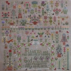 a cross stitch sample with flowers and birds on it's border, in the center is