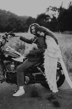 a man and woman are sitting on the back of a motorcycle together in black and white