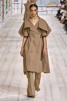 a model walks down the runway in a brown outfit