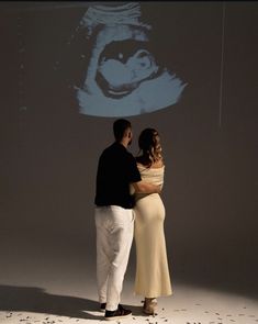 a man and woman standing in front of a projection screen with an image of a gorilla on it