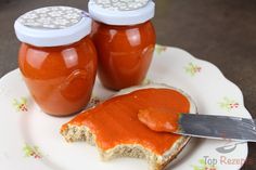 two jars of tomato sauce sitting on top of a plate next to a knife and bread