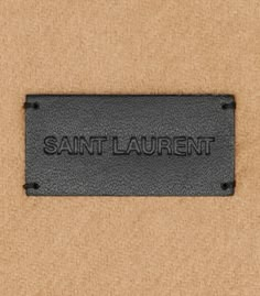 the name saint laurent is engraved in black on a tan background with dark metal fittings