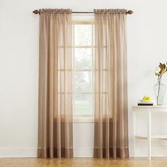 a white table with a vase and some flowers on it next to a window covered in sheer curtains