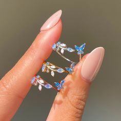 This ring is oh, so perfect. From the radiant array of blue crystals to the adjustable nature of the band, this ring has so many elements that only adds to it's elegance. Featuring a string of leaves on one end and a cute little butterfly on the other, our Perfect Petal Ring is just the piece to add to your garden of j Rings With Butterflies, Cute Rings And Bracelets, Cute Adjustable Rings, Butterfly Jewelry Rings, Butterfly Rings Aesthetic, Cute Butterfly Rings, Blue Rose Jewelry, Rings Cute Aesthetic, Prom Jewelry Rings