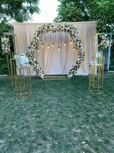 an outdoor ceremony setup with flowers and candles on the grass, surrounded by gold stands