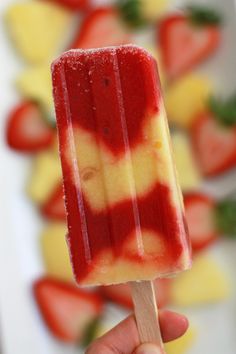 a hand holding a popsicle with strawberries on it