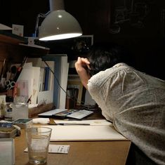 a man sitting at a desk in front of a lamp