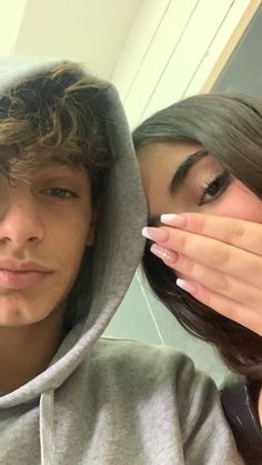 a young man and woman posing for a selfie in front of a bathroom mirror