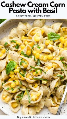 a bowl full of pasta with corn and spinach on top, next to a spoon