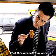 a man in a suit and tie eating food from a fork while sitting on a car seat