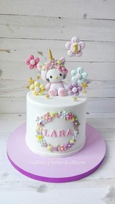 a hello kitty cake decorated with flowers and a unicorn