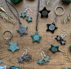 various earrings and pendants sitting on a table next to some rocks, pine needles and other items