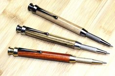 three different types of pens sitting on top of a wooden table