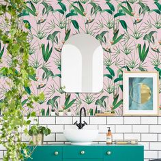 a bathroom with pink wallpaper and green cabinets