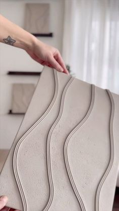 a woman is placing decorative tiles on top of a table in a living room with white walls