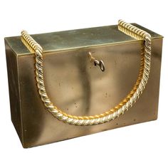 a gold colored metal box with a rope on the front and bottom, attached to it