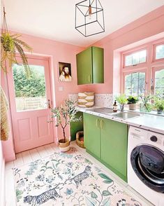 a kitchen with pink walls and green cabinetry has a rug on the floor next to the stove