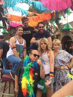 a group of people standing around each other in front of a building with colorful streamers