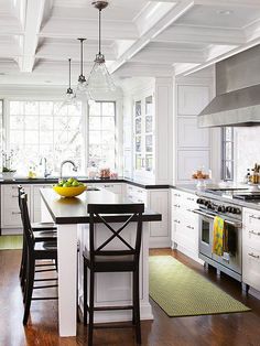 a kitchen with white cabinets and an island in front of a stove top oven next to a sink