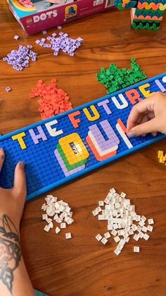 a person is playing with some legos on the table next to a board game