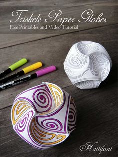 three paper globes sitting on top of a wooden table next to markers and pens