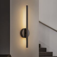 a wall mounted light on the side of a white wall next to stairs and steps