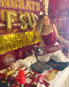 a woman sitting on top of a bed in front of a sign that says congrats g fsu