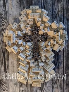 a cross made out of sheet music sits on top of a wooden table with the words hanging with a bookworm