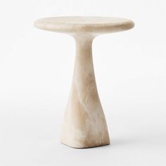 a small white table with a round base on it's side, against a white background