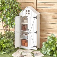 a small white garden shed next to some plants