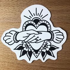 a sticker with an image of a heart and hands holding each other on a wooden surface