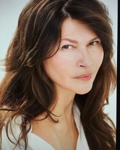 a woman with long brown hair is looking at the camera