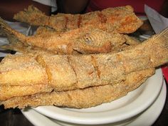 fried fish on a white plate sitting on a table