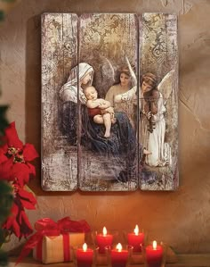 an angel painting on a wall next to candles and christmas tree with red poinsettis