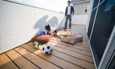 a man standing on top of a wooden deck next to a soccer ball and stuffed animals