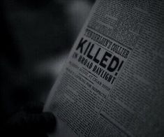 a person reading a newspaper with the word killed written on it in black and white