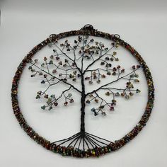 a tree of life with beads is displayed on a white surface in the shape of a circle