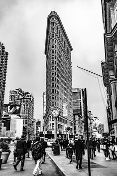 black and white photograph of people walking on the sidewalk in front of a tall building