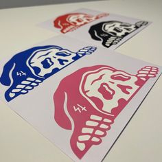 three stickers with different designs on them sitting on top of a white table next to each other