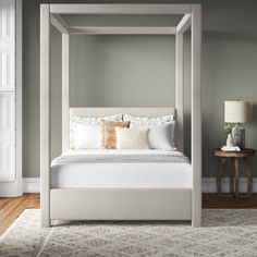 a white bed sitting on top of a wooden floor next to a lamp and table