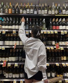 a woman is shopping for wine in a store