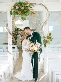 a bride and groom kissing under an arch decorated with flowers